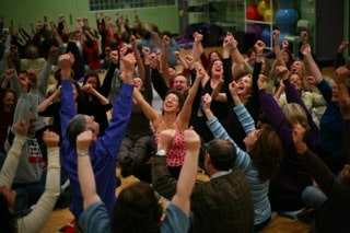 Personne levant les mains dans un élan de rire et de joie collective, représentant la libération et l’énergie d’un atelier de rire bien-être.