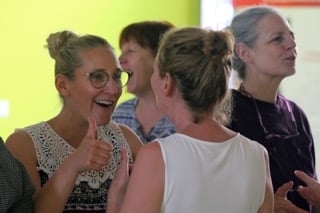 participants levant les bras et disant oui avec enthousiasme lors d’un exercice de rire bien-être, exprimant confiance et gratitude