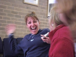 Femme riant de bon cœur pendant une activité de groupe, symbole de convivialité, d’écoute mutuelle et de détente partagée.